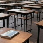 Sala de aula vazia em escola pública brasileira com carteiras antigas e quadro negro, representando reajuste no piso de professores.