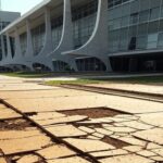 Calçada quebrada e escadas sem rampa em prédio governamental de Brasília, expondo negligência em acessibilidade para deficientes e autistas no DF.