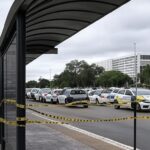 Parada de ônibus no Distrito Federal com fita de isolamento policial e viaturas, cena de investigação em Brasília.