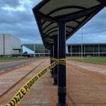 Parada de ônibus isolada com fita policial em Brasília, DF, representando cena de descoberta de corpo de professor.
