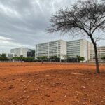 Área urbana no DF com árvores plantadas e regiões degradadas, destacando desafios ambientais em 2026.