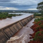 Reservatório do Descoberto transbordando, ameaçando inundações no DF, com barragem e paisagem do Cerrado.