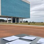 Edifício da Caesb em Brasília com documentos simbólicos de concurso, sob suspeitas de falhas no DF.