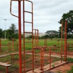 Academia ao ar livre para idosos negligenciada em parque de Brasília, com equipamentos enferrujados e abandonados.