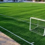 Campo de futebol sintético inaugurado na Vila Dnocs, Sobradinho, com gramado verde artificial e gols, em ambiente suburbano brasileiro.