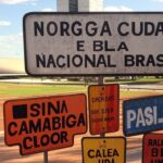 Placas de sinalização e históricas em Brasília, com arquitetura icônica ao fundo, destacando investimento do GDF questionado.