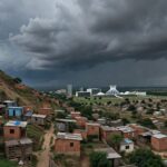 Vista de áreas de risco no Distrito Federal, com moradias precárias em encostas, afetando comunidades locais.