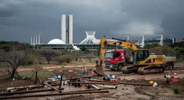 Obras de saneamento em Brasília com tubulações e equipamentos parados, destacando atrasos e riscos hídricos no DF.