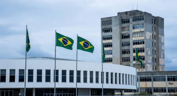 Fachada da CLDF em Brasília com hospital deteriorado ao fundo, expondo falhas crônicas no sistema de saúde do DF.