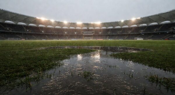 Gramado de futebol alagado por chuva intensa no Candangão, com poças d'água e grama molhada em estádio no DF.