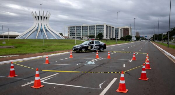 Cena de rua em Brasília com sinais de atropelamento, cones de trânsito e viatura policial, representando acidente no Distrito Federal.