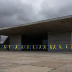 Edifício da CLDF em Brasília com símbolos do Dia da Síndrome de Down, destacando críticas por falta de políticas reais.