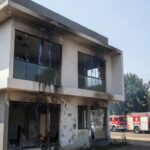 Casa residencial em Brasília danificada por incêndio, com viaturas de bombeiros ao fundo.