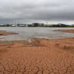 Reservatório com nível baixo de água no DF, destacando crise hídrica que ofusca premiação da Caesb.