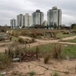Parque abandonado em Águas Claras com vegetação seca, lixo e bancos quebrados, expondo negligência com áreas verdes.