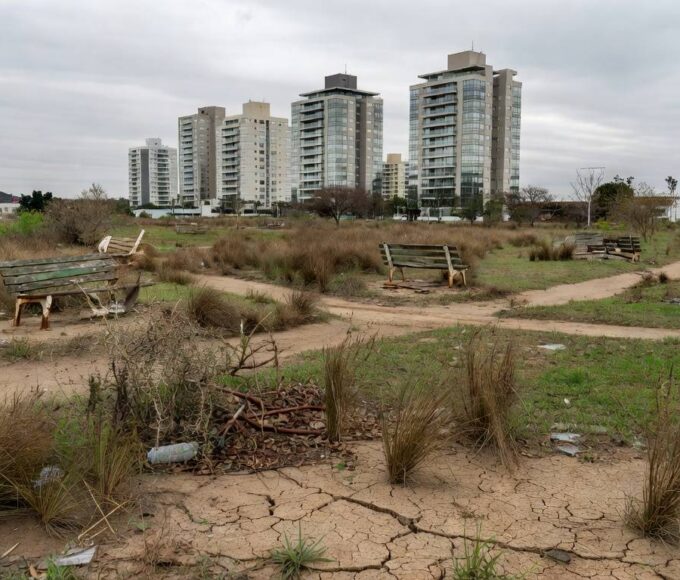 Parque abandonado em Águas Claras com vegetação seca, lixo e bancos quebrados, expondo negligência com áreas verdes.