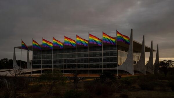Fachada da CLDF em Brasília com bandeiras do arco-íris sob luz sombria, simbolizando discriminação