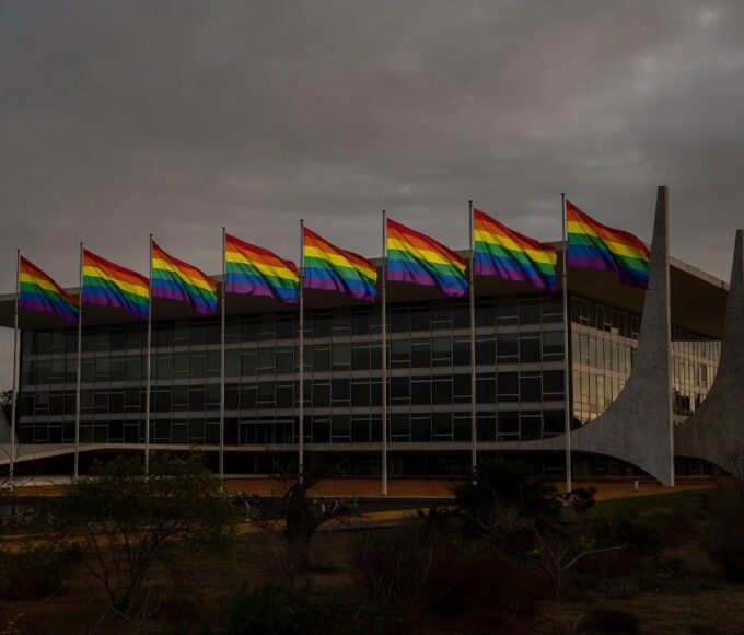 Fachada da CLDF em Brasília com bandeiras do arco-íris sob luz sombria, simbolizando discriminação