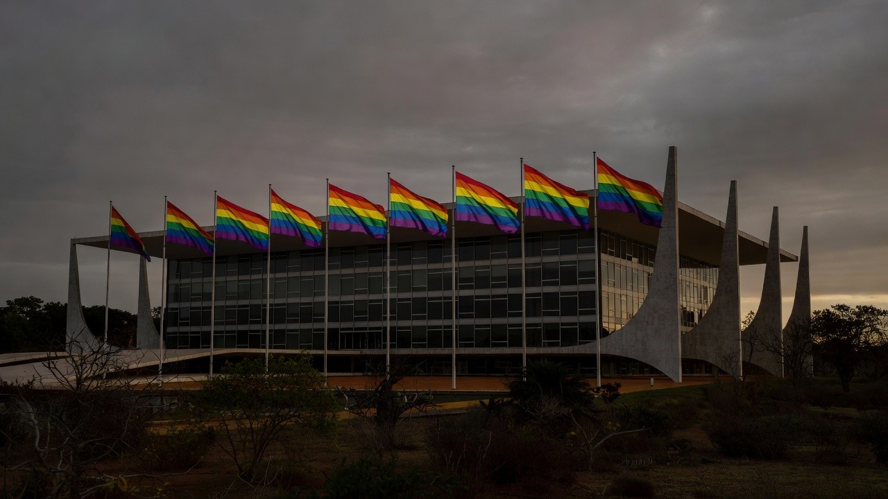Fachada da CLDF em Brasília com bandeiras do arco-íris sob luz sombria, simbolizando discriminação